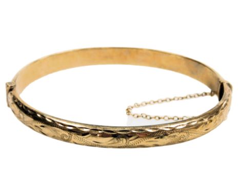A 9ct gold bangle, with engraved foliate decoration, on snap clasp, with safety chain as fitted, 8.4g. 