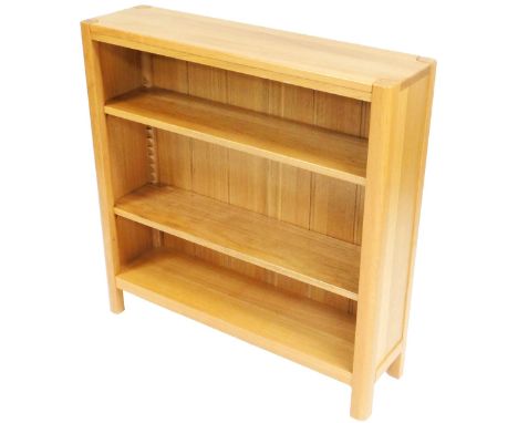 A light oak bookcase, with a signature leaf motif to the top, with three shelves, raised on stiles, 90cm high, 90cm wide, 25c