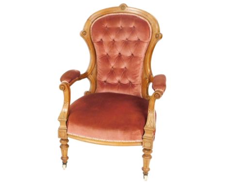 A Victorian mahogany spoon back open armchair, upholstered in red button back draylon, raised on turned legs, brass capped on