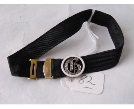 An antique black wrist band with gold mounts and set with  a diamond, gold and enamel catch     