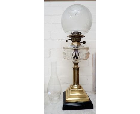 A Victorian brass column oil lamp with cut reservoir, glass chimney and shade on stepped base and ebonized plinth 