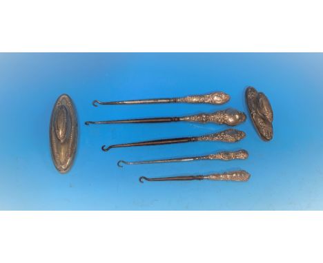 Three silver handled steel button hooks; two nail buffers 