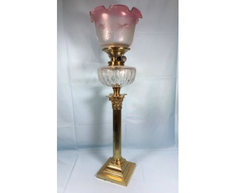 A 19th century Corinthian column oil lamp with dimpled glass reservoir and etched folded cranberry shade, height of lamp 22" 