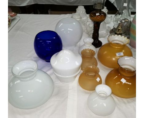 Two glass oil lamps and a selection of glass oil lamp shades and other glass shades 