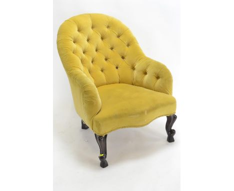 A button back armchair, raised on mahogany supports, with yellow upholstery 
