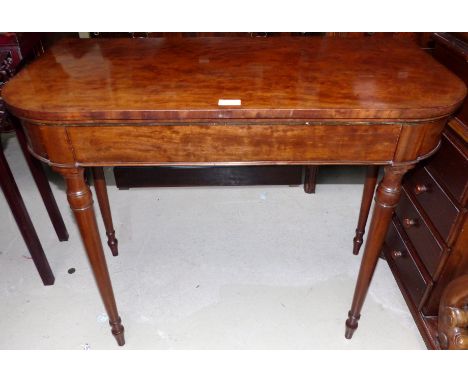 An early 19th century mahogany fold over baize lined card table on turned legs