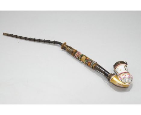 A 19th century Continental porcelain pipe, with floral decoration and brass mounts, the pipe stem with beadwork and long horn