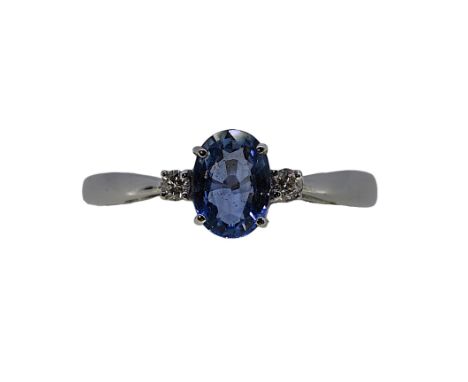 An 18ct gold sapphire and diamond ring, oval faceted sapphire approximately 7.1 x 5.1mm, flanked by two diamonds, size O, hal
