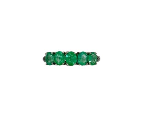 A 9ct gold five stone emerald ring, five oval faceted emeralds, flanked by a trio of diamonds either side, width 5.3mm, size 
