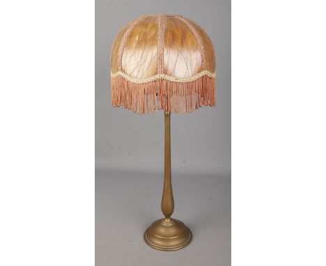 A brass rise and fall table lamp in the style of Benson with fringed shade.  