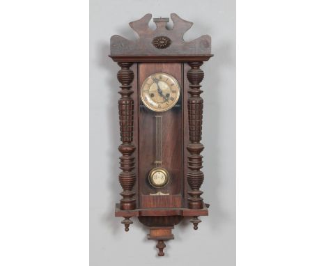 A mahogany wall clock with enamel face, turned columns and carved detail.Hx86cm approx  