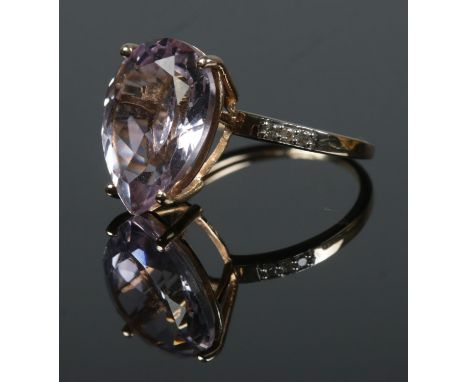 A 9ct gold dress ring set with a large pink coloured stone, possibly Morganite. Having three small diamonds to each shoulder.