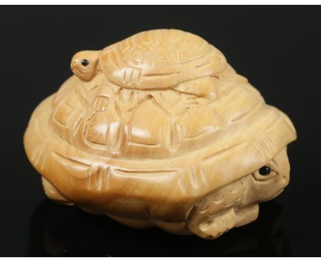 A hand carved hardwood netsuke of a baby turtle sitting on an adult turtle.  