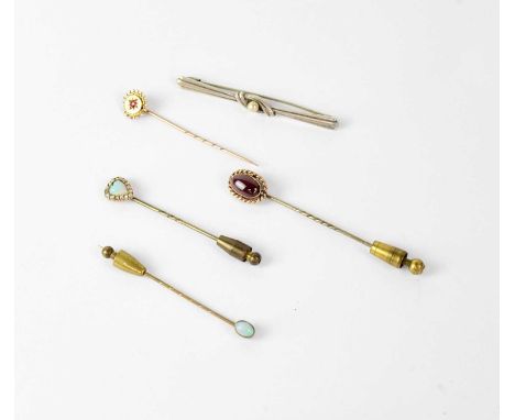 Four yellow metal stick pins, one with cabochon amethyst in rope mount, heart-shaped opal with diamond surround, small oval o