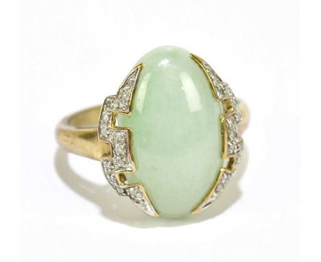 A yellow metal dress ring set with a pale green jade-coloured stone, flanked by a melee of white stones, stamped 9K, size R, 