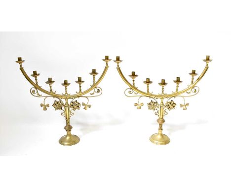 A pair of late 19th century ecclesiastical brass seven-light candlesticks with scroll and foliate decoration on knopped and w