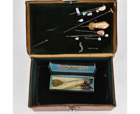 Various vintage and antique hat pins and lapel pins, including gold examples, in a leather box with initials 'NB'. 