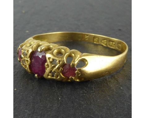 An 18ct gold ring, claw set ruby flanked by two small rubies separated by two rows of two tiny diamonds, size N, approx. 2.2g