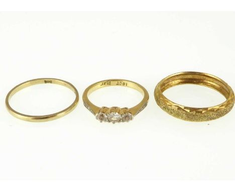 Three gold rings comprising an 18ct dress ring set with three white stones, size K, approx. 2.6g, and two 9ct gold band rings
