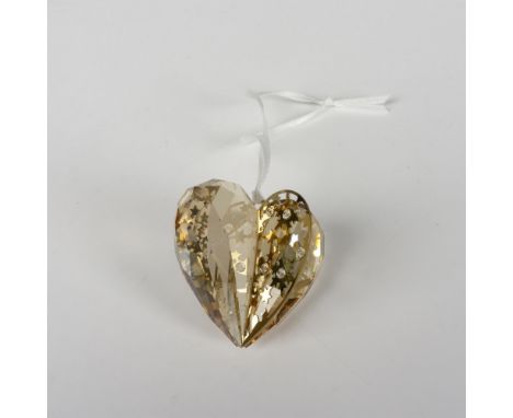 A 3D gold-toned metal and faceted crystal heart shaped adornment, decorated with crystal chaton's and comes on a white satin 