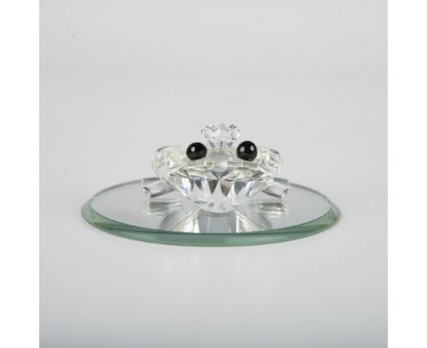 A clear faceted figure of a sitting frog wearing a small crown and black eyes. Part of the Beauties of the Lake collection. I