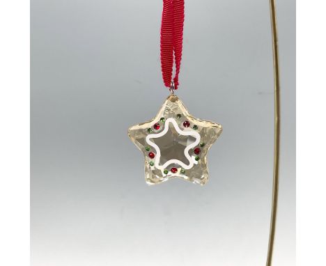 A gold-toned crystal star-shaped decor with white printing detailing, and red and green crystal accents. Swarovski stamp. Thi