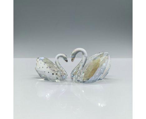 Two clear faceted figures of endearing swans, forming a heart when their metal beaks touch, with the female adorned with clea