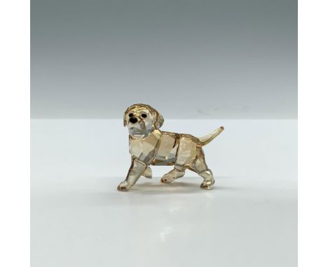 A clear faceted figure of a golden-hued young dog, attentively standing with one paw delicately lifted. Artists signature ins