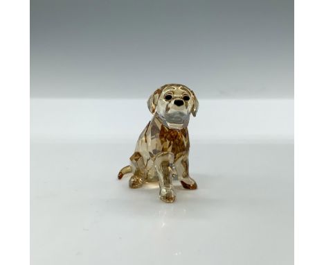 A clear faceted figure of a golden-colored young dog in a sitting position with black eyes and nose. Artists signature inscri