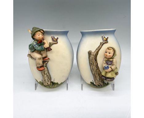 A set of 2 porcelain hand painted wall flower vases. One depicts a boy playing the horn, and the other depicts a girl holding