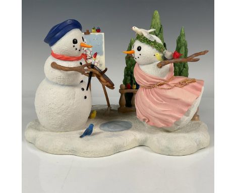 A whimsical Holiday tableau figurine of a snowman artist painting a portrait of his muse. Wonderful details, such as the proc
