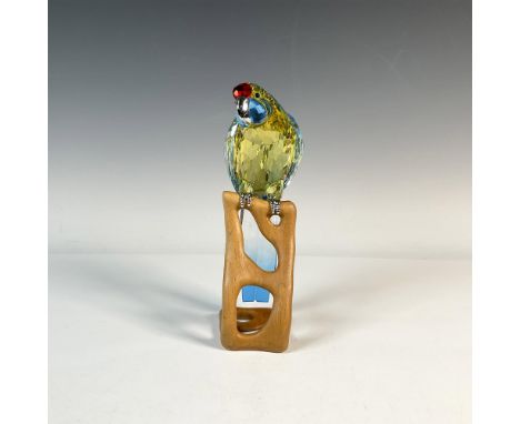 A striking clear faceted figure of a parrot, vibrant in yellow, blue, and red hues, with a metal beak and feet, and black eye