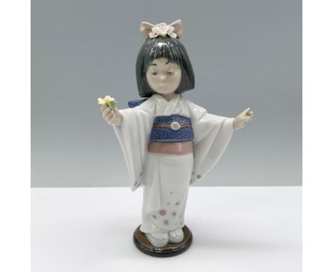 A radiant young girl in a white, blue, and pink kimono, arms outstretched, gracefully holding a delicate flower. Lladro backs