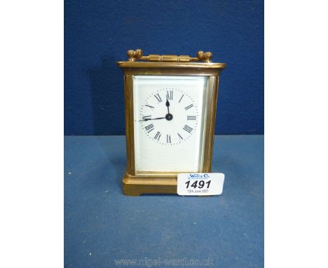 A Carriage Clock having a brass framed and bevelled glass case, the enamel face with Roman numerals, and having the balance w