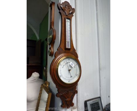 A carved Oak framed aneroid Barometer and thermometer, 35'' long overall.