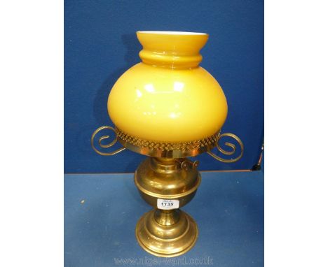 An antique Brass oil Lamp with amber coloured shade sitting on brass supports, twin burner, 18" tall.