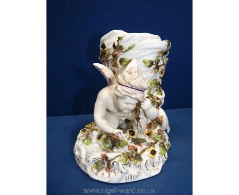 A china centrepiece of a cherub next to a tree trunk with encrusted flowers and leaves, marked 'S' with a line through on bas