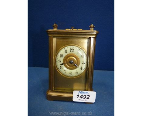 A Carriage Clock having a heavy brass and bevelled glass case with a brass face, the chapter ring marked with the hours in Ar