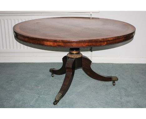 A Regency rosewood breakfast table with circular satinwood banded tilting top, on gilt decorated turned pedestal and scroll s