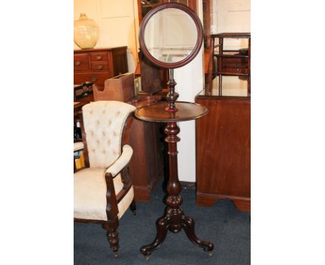 A Victorian mahogany shaving stand with circular adjustable mirror and shelf, on turned baluster stem, outswept tripod legs a