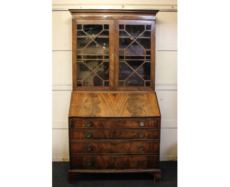 A George III mahogany bureau bookcase with twin panelled doors enclosing three shelves, above flame veneered fall, enclosing 