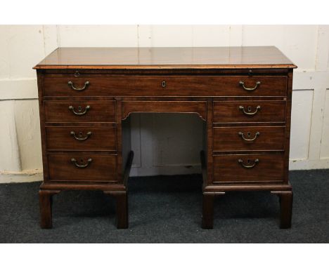 A George III mahogany desk with slide, kneehole drawer and two rows of three short drawers with brass drop handles, on tall b