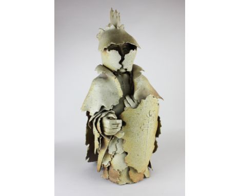 A Gil Tregunna art pottery figure of a knight in heavy armour, with sword and helmet, paper label, 55cm high, (a/f)