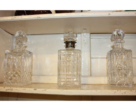 A silver mounted glass decanter with engraved inscription to the collar, and two other rectangular shaped glass decanters wit
