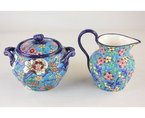 A French Longwy pottery sugar bowl and jug, both with all-over floral decoration on blue ground, marks to bases