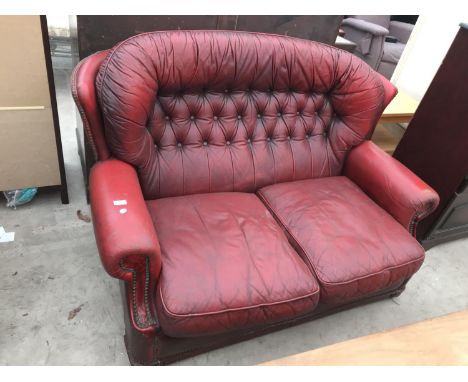 AN OXBLOOD LEATHER BUTTON BACK TWO SEATER SOFA 