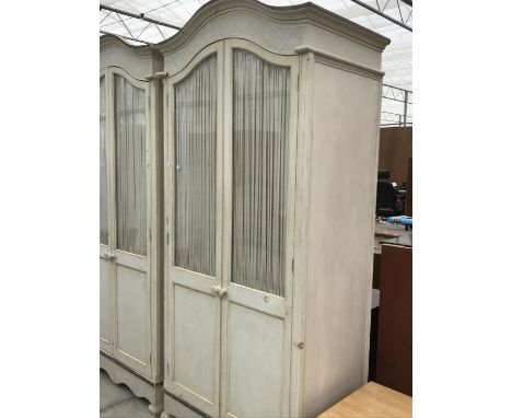 A CREAM PAINTED WARDROBE WITH TWO GLAZED DOORS HAVING INNER BUNCHED CURTAINS 