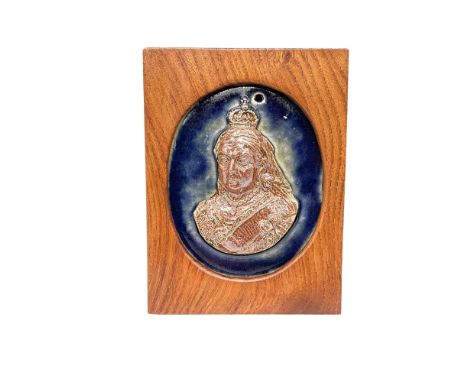 Housed in a wood frame, a raised salt glaze portrait of the queen of the United Kingdom of Great Britain and Ireland for over
