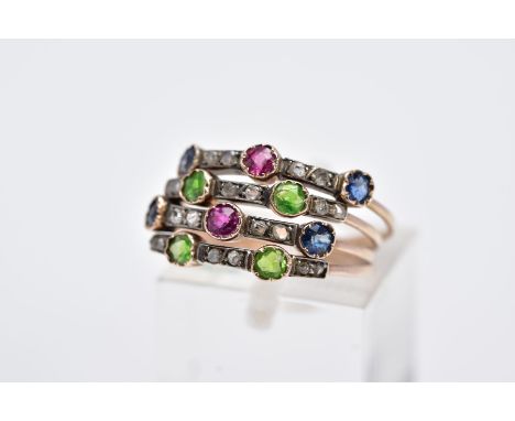 A GEM SET MULTI BAND RING, designed with four bands, each band is set with circular cut blue sapphires, rubies, peridot or am