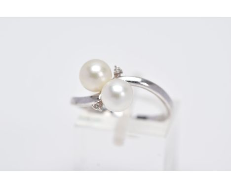 A 9CT WHITE GOLD RING, of a crossover design set with two cultured pearls flanked with round brilliant cut diamonds, plain po